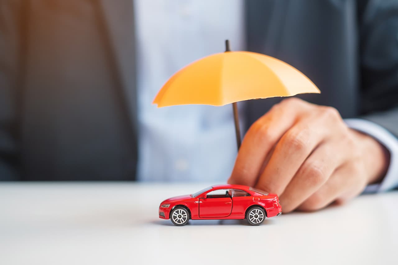 テーブルの上に赤いミニカーを持つ男性の手